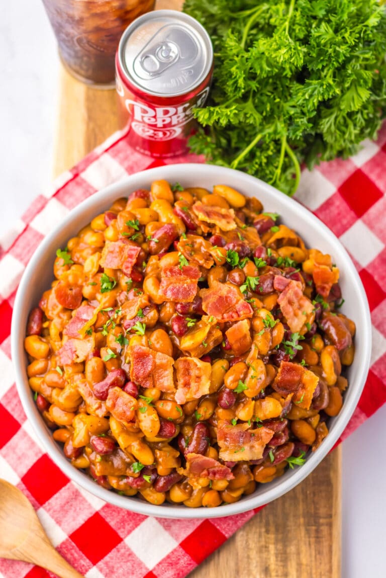 Bowl of baked beans topped with chopped bacon and parsley.