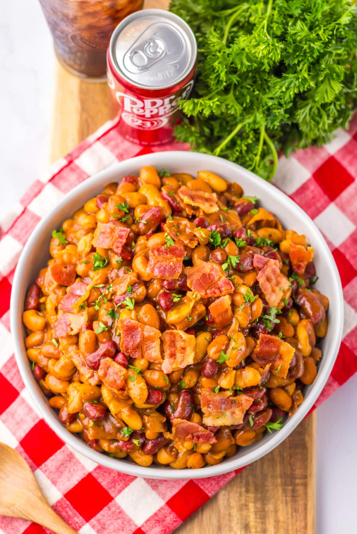 Bowl of baked beans topped with chopped bacon and parsley.