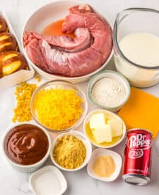 Ingredients for slow cooker Dr Pepper pulled pork mac and cheese sliders including pork, soda, cheese, and buns.