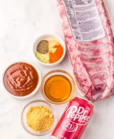 Ingredients for slow cooker Dr Pepper ribs including pork ribs, barbecue sauce, seasonings, and soda.