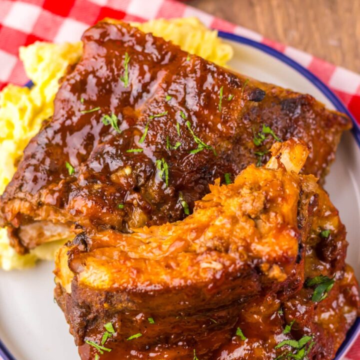 Cooked ribs stacked and coated in glossy sauce.