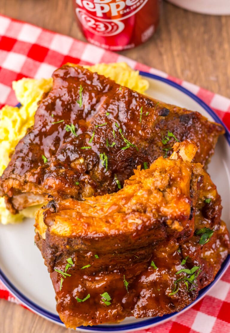 Cooked ribs stacked and coated in glossy sauce.