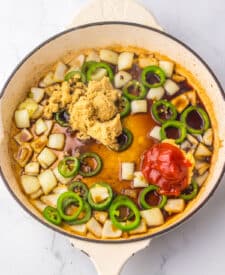 Broth and sliced jalapenos cooking in a skillet.
