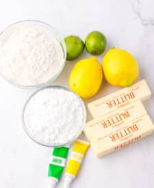 Ingredients for lemon lime meltaway cookies including citrus and powdered sugar.