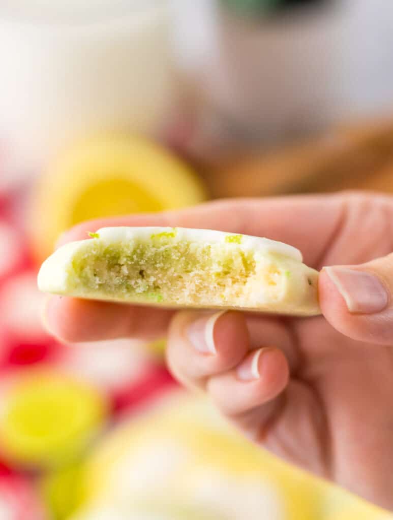 Hand holding a lemon lime meltaway cookie showing soft texture.