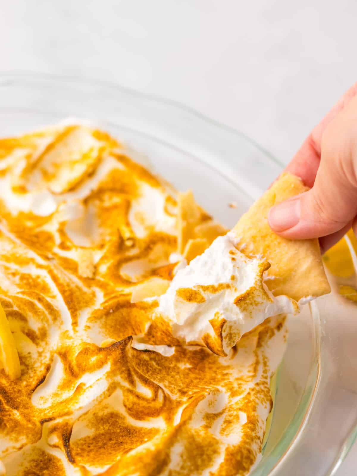 Cracker dipping into lemon meringue pie dip.