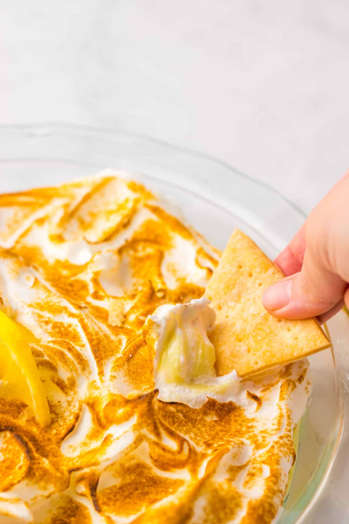 Cracker dipping into lemon meringue pie dip.
