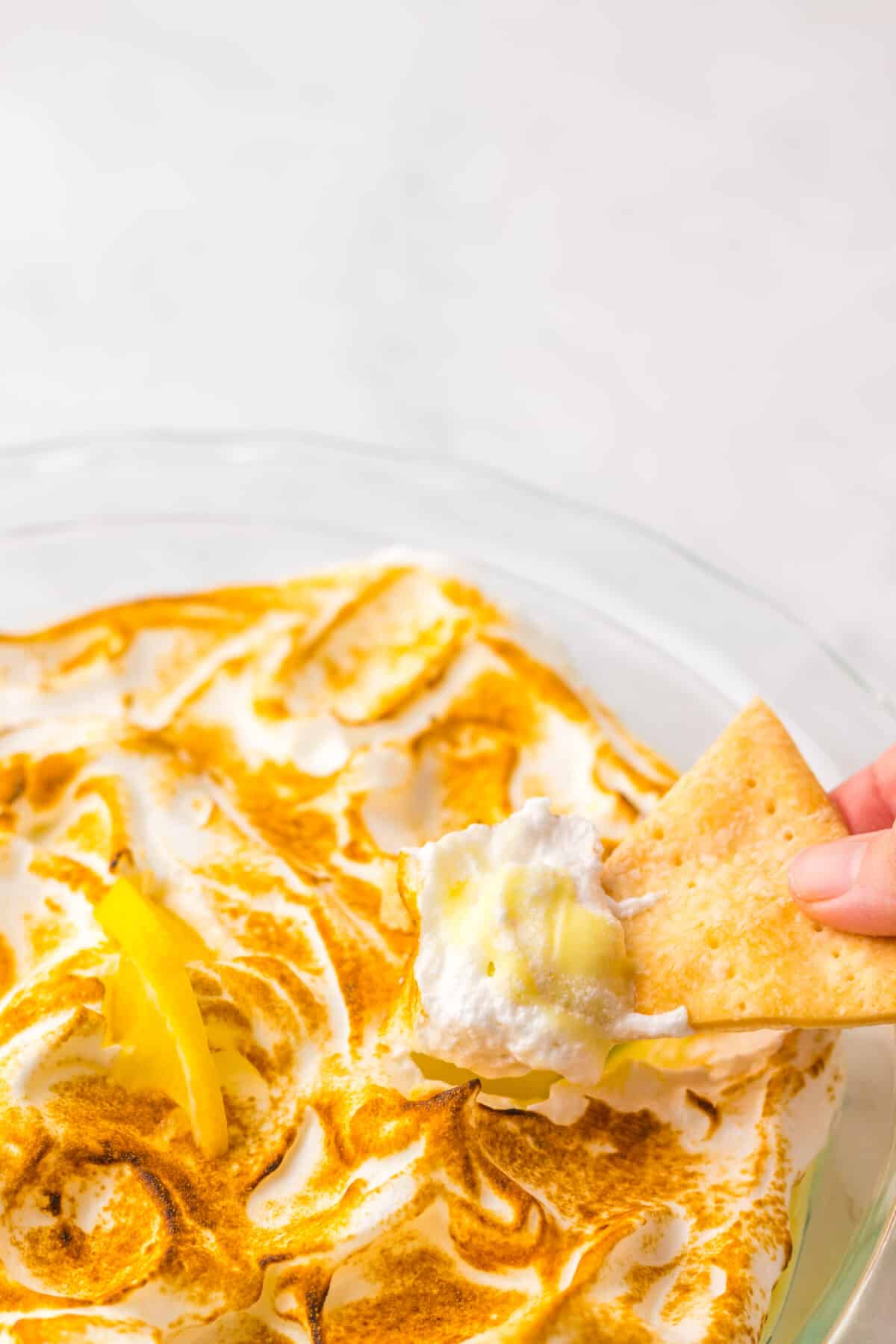 Cracker dipping into lemon meringue pie dip.