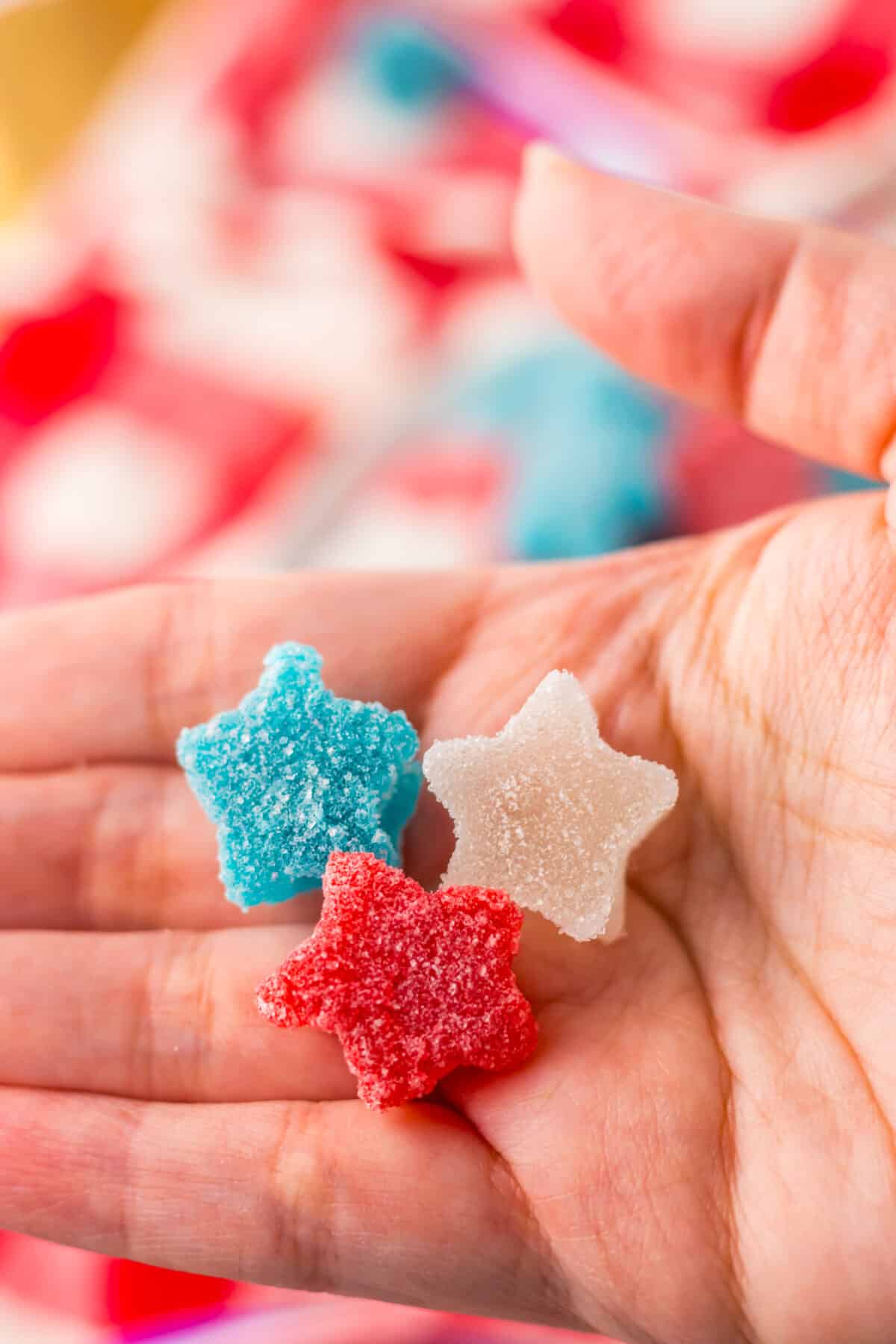 Hand holding star-shaped red and blue gumdrops.