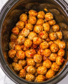Meatballs cooking in the slow cooker in rich birria sauce.