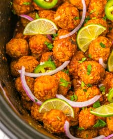 Close-up of saucy birria meatballs topped with fresh cilantro and lime.