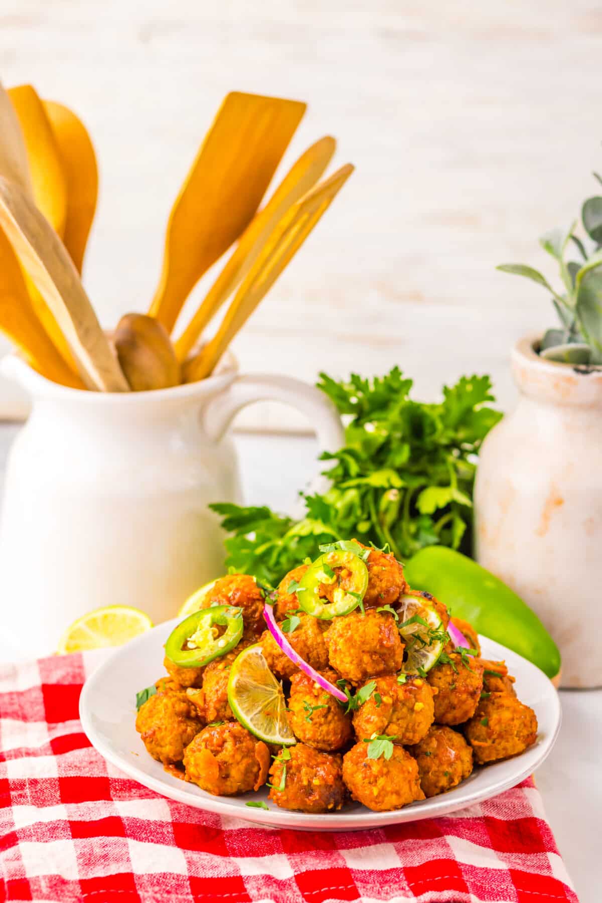 Slow cooker birria meatballs plated with fresh herbs and lime.