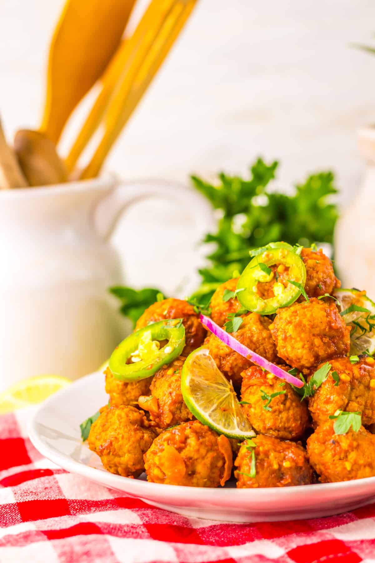 Birria meatballs served on a platter with lime wedges and fresh toppings.