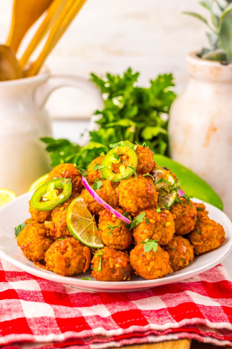Birria meatballs served on a platter with lime wedges and fresh toppings.