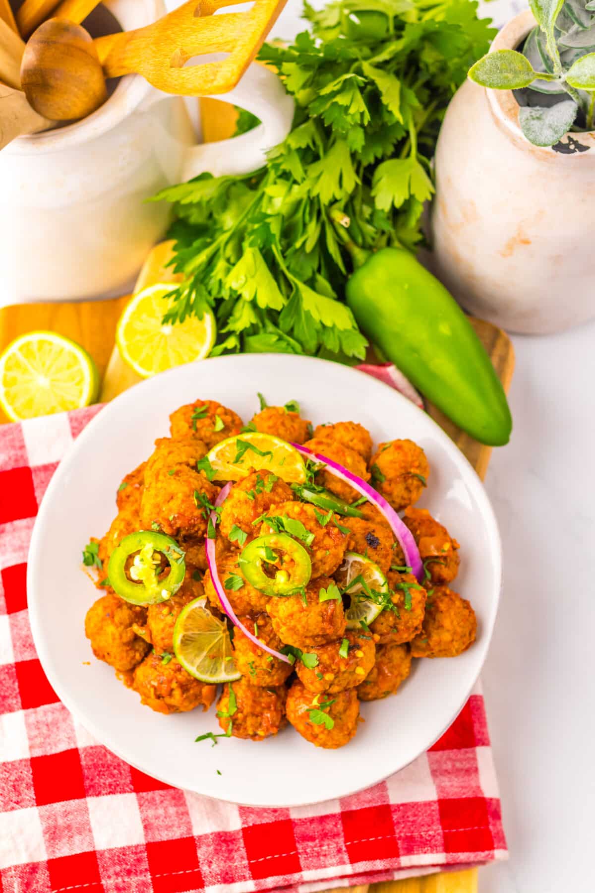 Slow cooker birria meatballs plated with fresh herbs and lime.