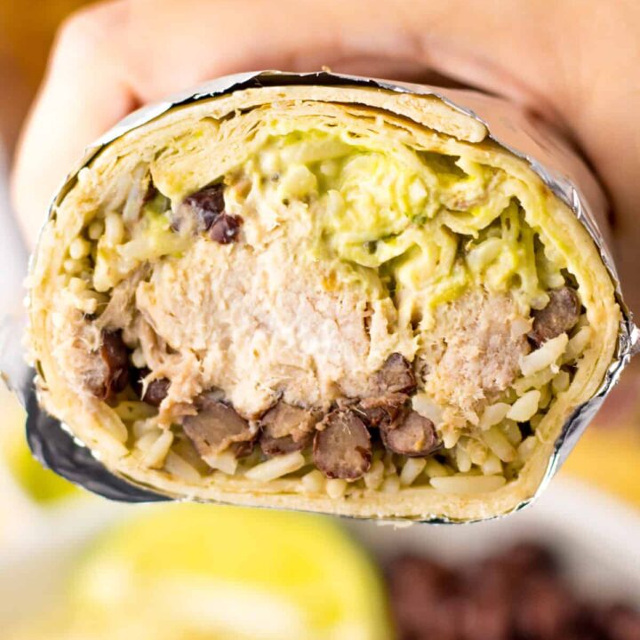 Close-up of slow cooker carnitas burrito with rice and guacamole.
