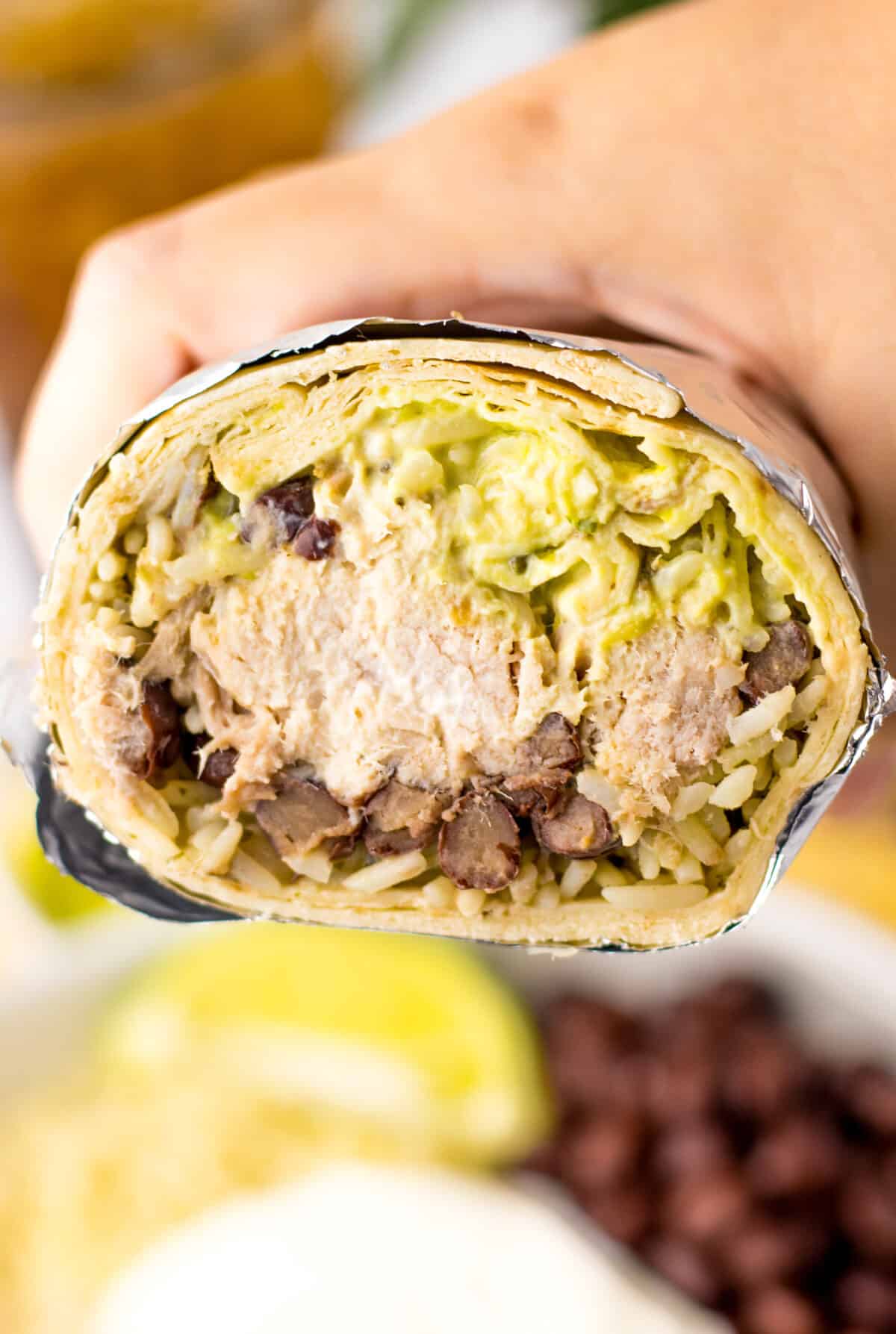 Close-up of slow cooker carnitas burrito with rice and guacamole.