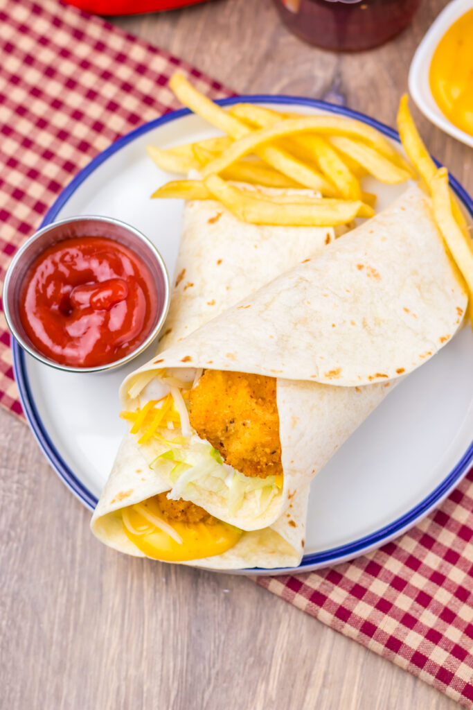 Homemade crispy chicken snack wrap meal with fries and ketchup.