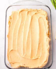 Refried bean layer spread into a baking dish for taco dip.