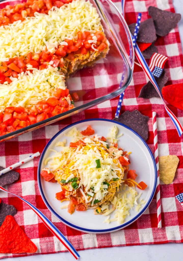 Patriotic Flag Taco Dip topped with tomatoes, cheese, and blue tortilla chips.