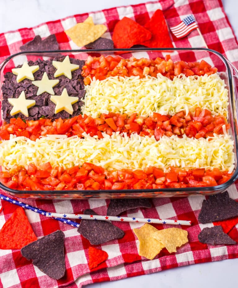 Red, white, and blue taco dip with cheese stars and tomato stripes.