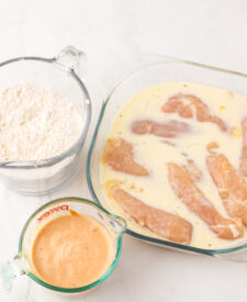 Chicken tenders marinating in buttermilk before breading.