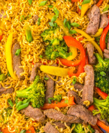 Beef, ramen, and vegetables tossed together with savory sauce on a sheet pan.