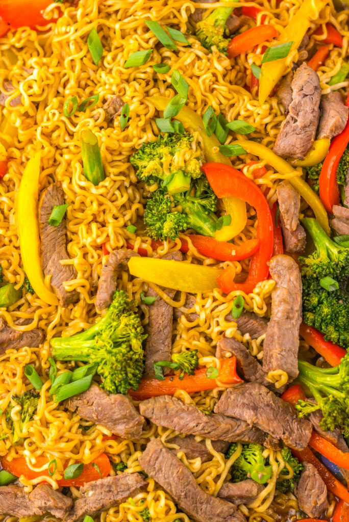 Beef, ramen, and vegetables tossed together with savory sauce on a sheet pan.