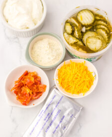 Ingredients for Viral Pickle Dip including cream cheese, sour cream, ranch seasoning, shredded cheddar cheese, and chopped dill pickles.