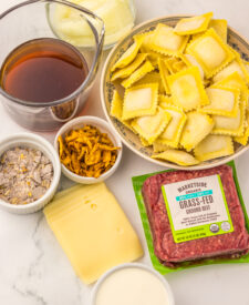 Ingredients for Slow Cooker French Onion Ravioli including frozen ravioli, French onion soup, broth, cheese, and seasonings.