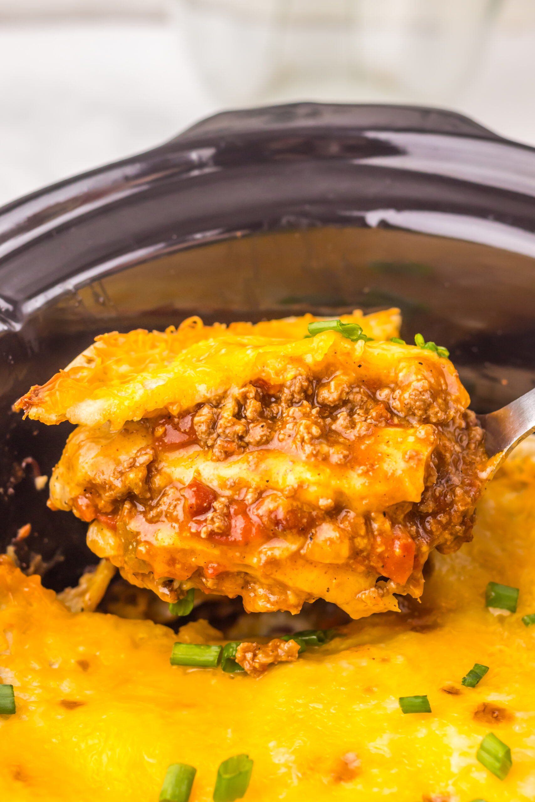 Close-up of a serving of Chili Cheese Enchilada Bake scooped from the slow cooker.