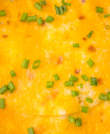 Slow Cooker Chili Cheese Enchilada Bake topped with melted cheddar cheese and green onions.