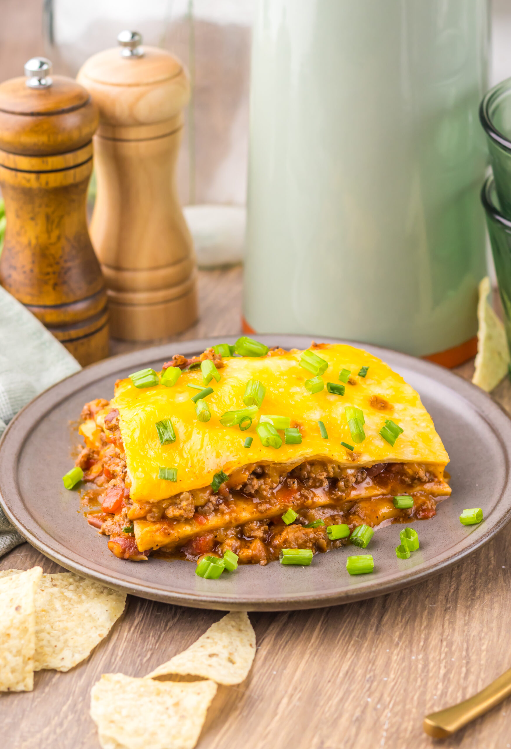 Slow Cooker Chili Cheese Enchilada Bake served on a plate with melted cheddar and green onions.
