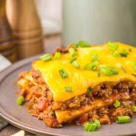 Finished Slow Cooker Chili Cheese Enchilada Bake with beef, tortillas, melted cheese, and green onions.
