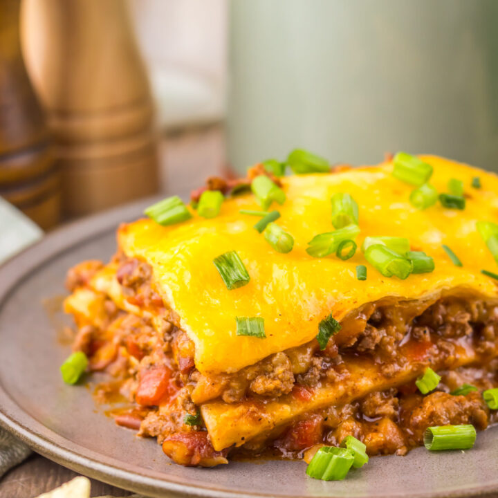 Finished Slow Cooker Chili Cheese Enchilada Bake with beef, tortillas, melted cheese, and green onions.