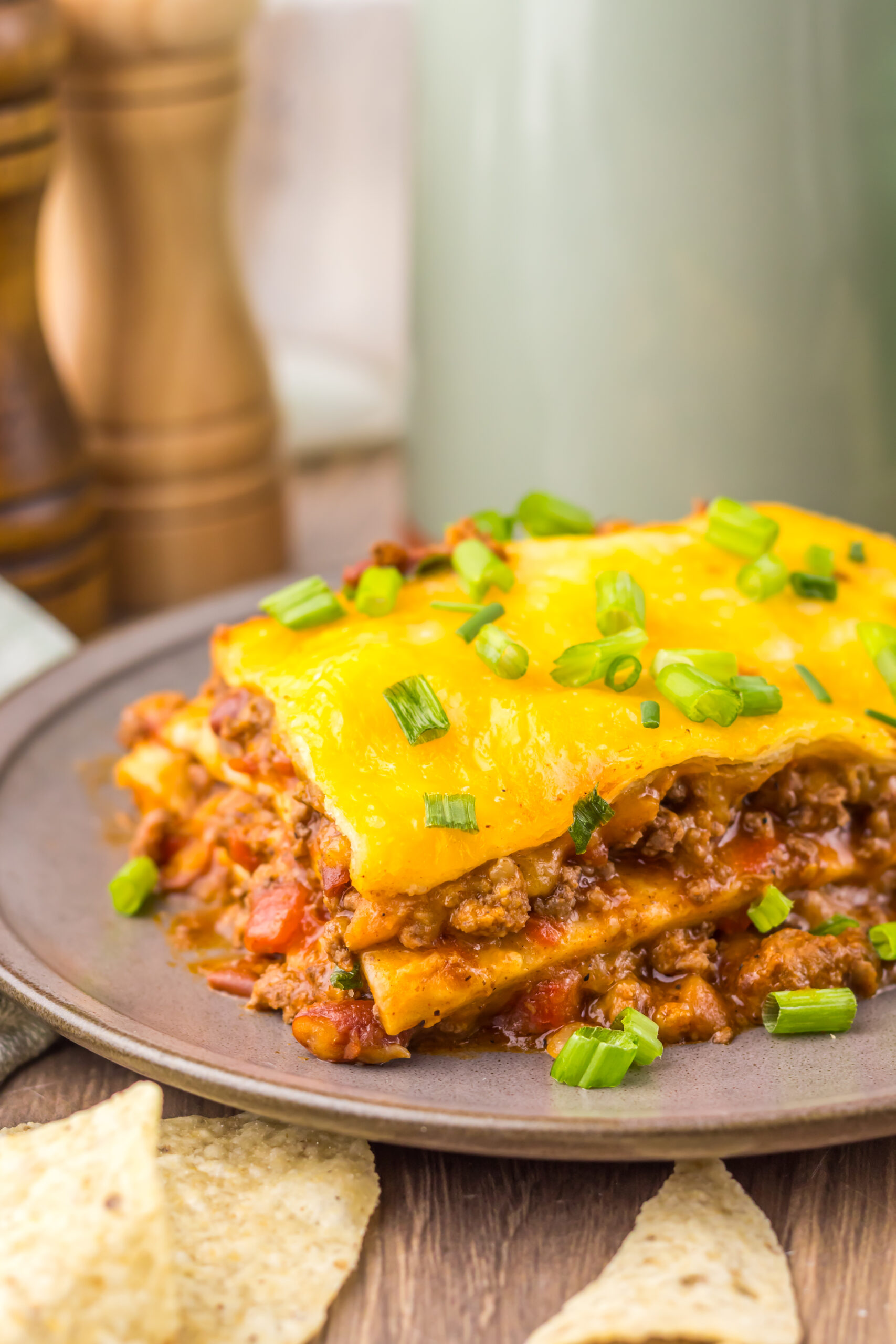 Finished Slow Cooker Chili Cheese Enchilada Bake with beef, tortillas, melted cheese, and green onions.