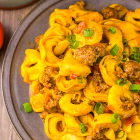 Close-up of Slow Cooker Taco Tortellini with cheesy tortellini, taco beef, and green onions.