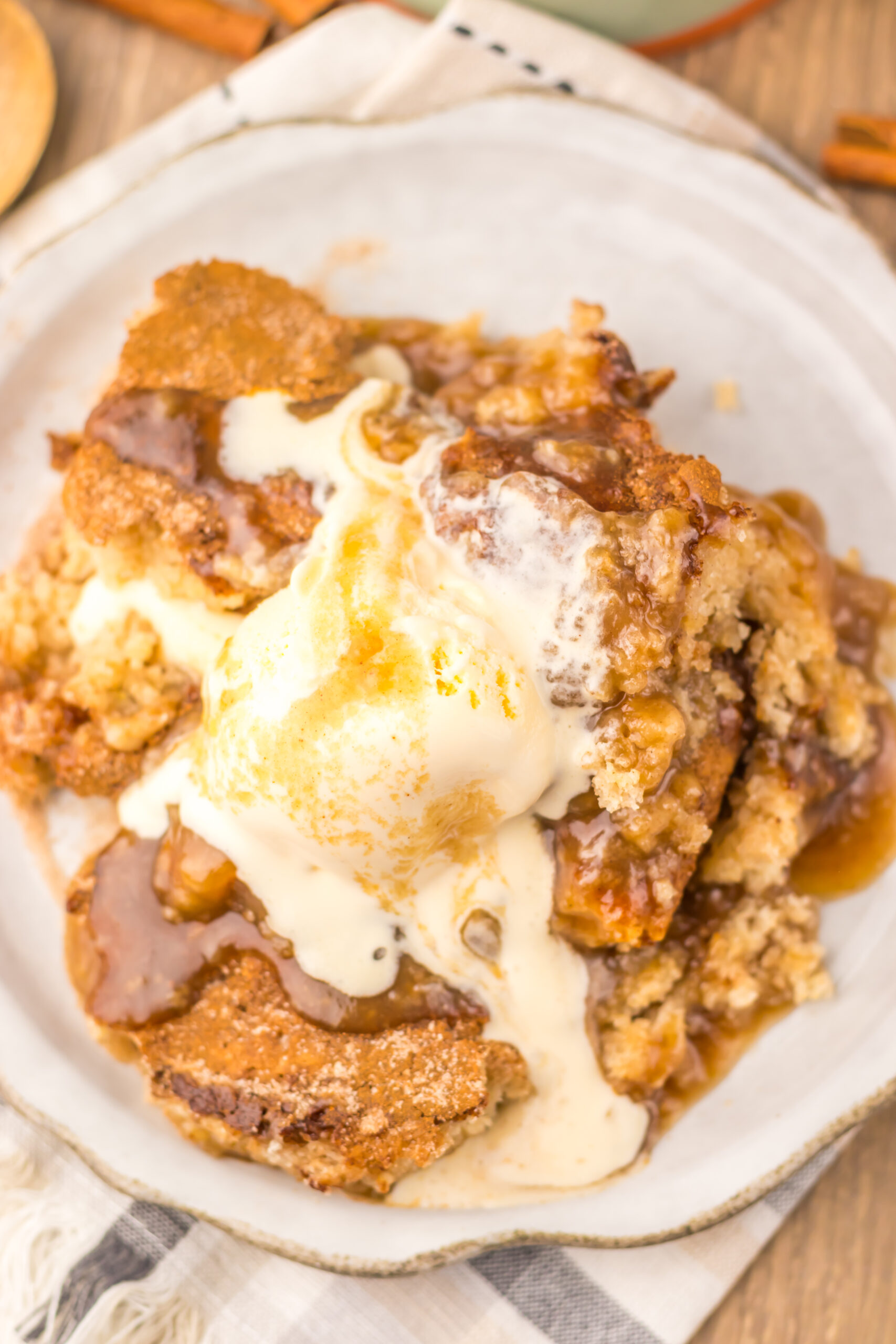 Close-up of warm Snickerdoodle Cobbler with gooey cinnamon filling and melting vanilla ice cream.