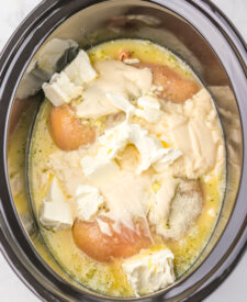 Chicken breasts, cream cheese, and Alfredo sauce added to the slow cooker.