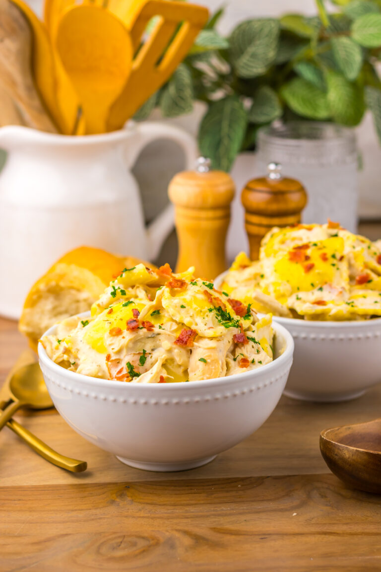 Creamy Crack Chicken Alfredo Ravioli topped with bacon and served with bread.