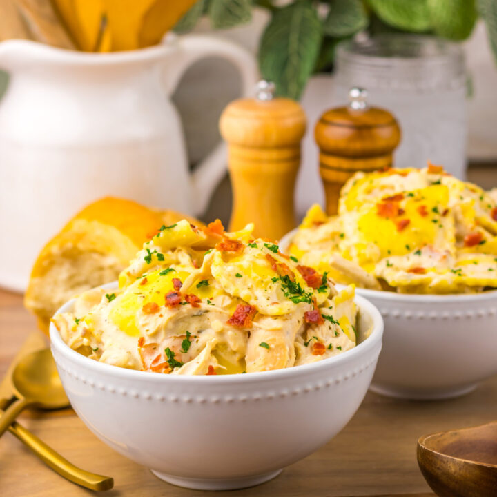 Creamy Crack Chicken Alfredo Ravioli topped with bacon and served with bread.