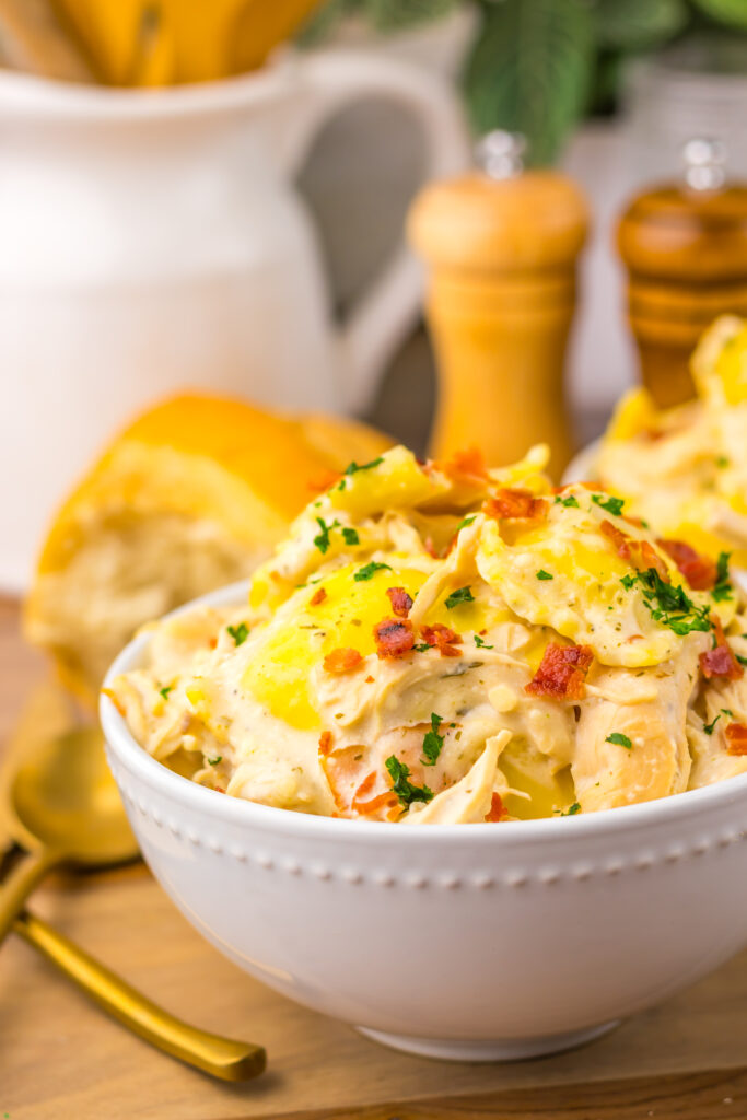 Bowl of cheesy Slow Cooker Crack Chicken Alfredo Ravioli on the dinner table.