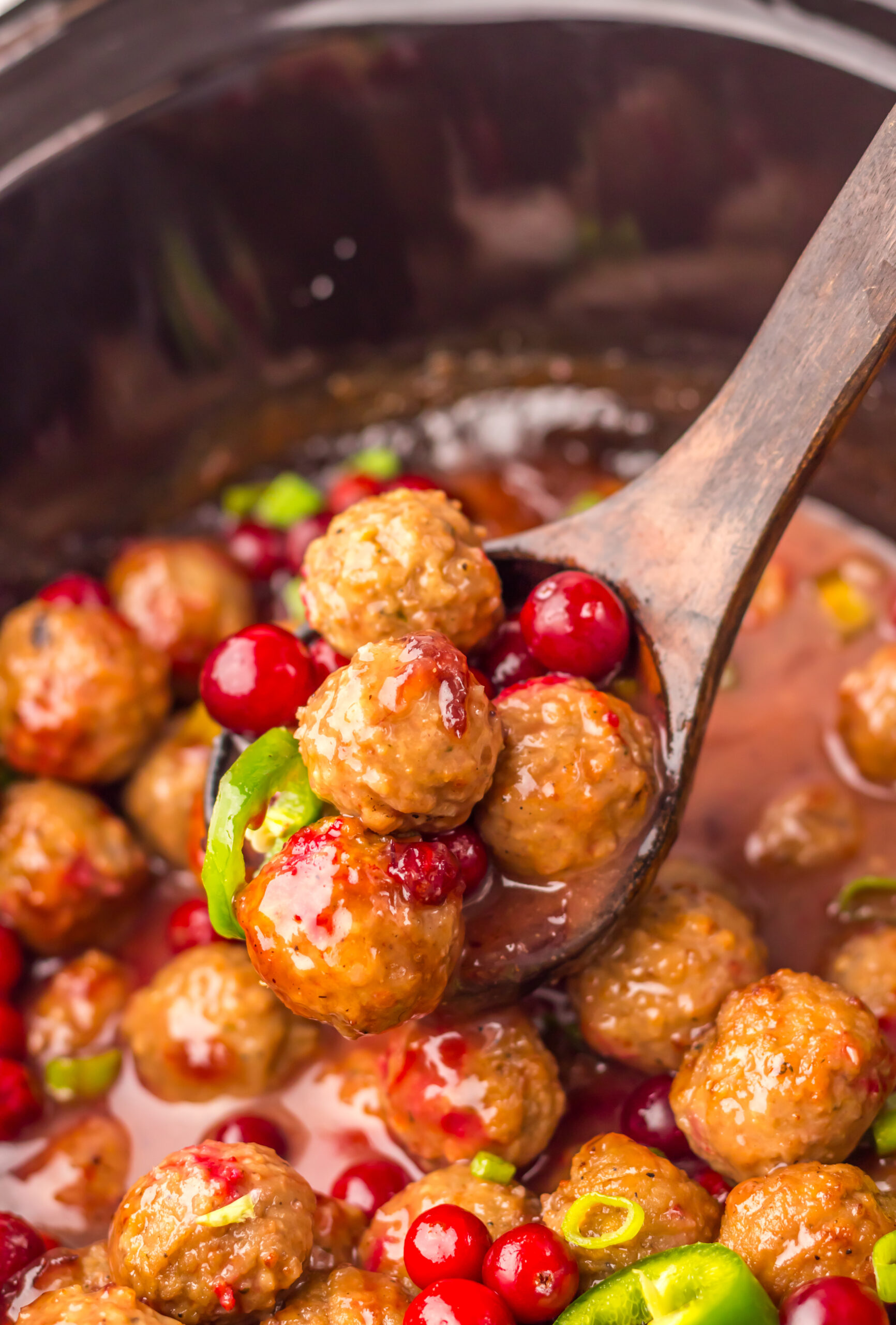 Cranberry Jalapeño Meatballs cooking in a glossy sweet and spicy sauce in the slow cooker.