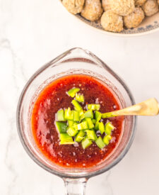 Cranberry jalapeño sauce in a glass bowl topped with chopped fresh jalapeños.