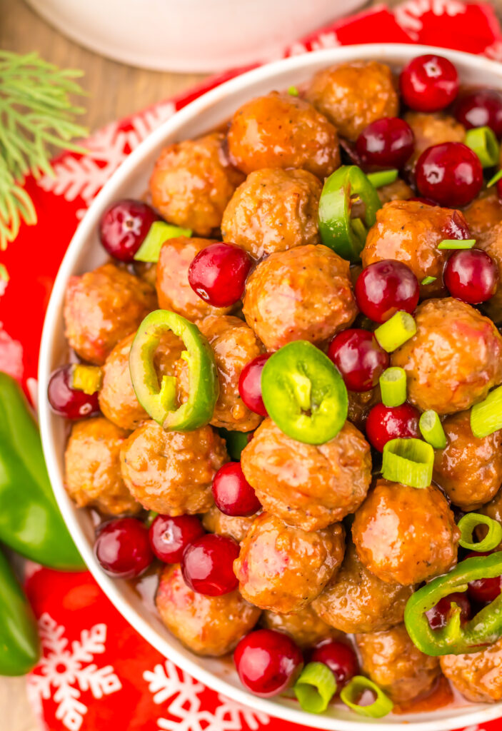 Close-up of Slow Cooker Cranberry Jalapeño Meatballs garnished with fresh green jalapeños.