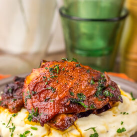 Close-up of glazed Slow Cooker Honey Bourbon Chicken Thighs topped with herbs.