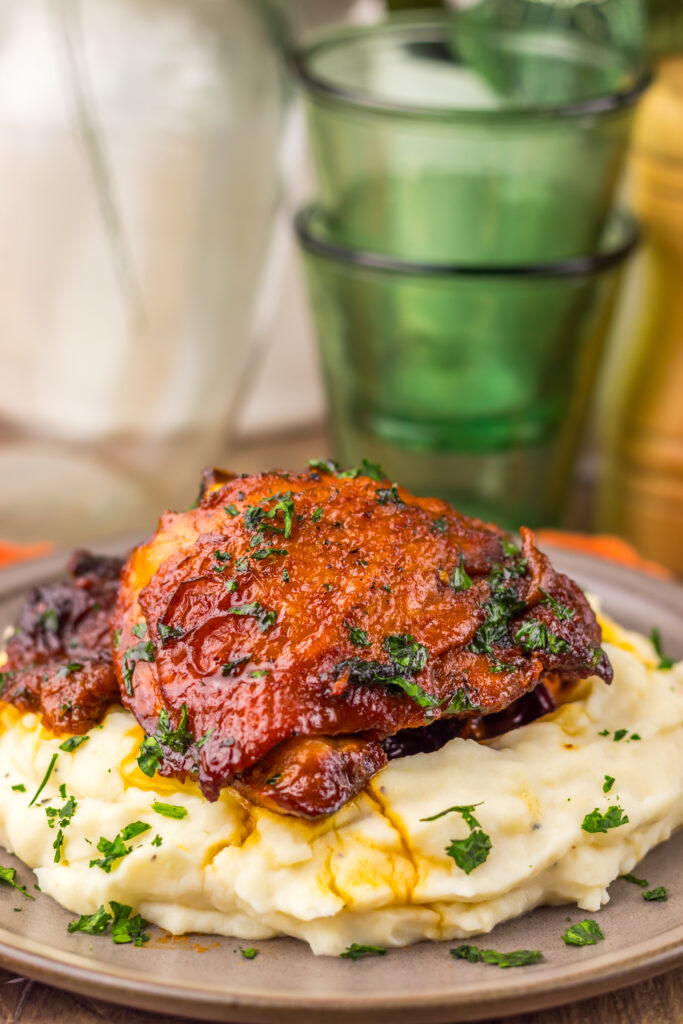 Close-up of glazed Slow Cooker Honey Bourbon Chicken Thighs topped with herbs.