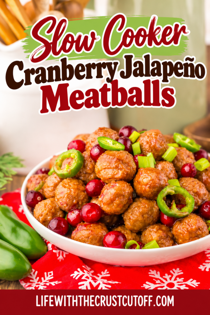 Slow Cooker Cranberry Jalapeño Meatballs coated in a glossy sauce and served in a white bowl with fresh cranberries, sliced jalapeños, and chopped green onions on a festive red snowflake napkin.